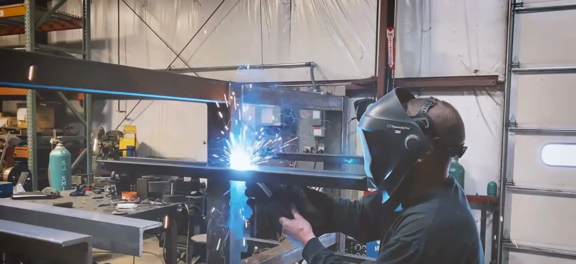Riverfront Machine welder in a hood running a weld bead, sparks flying